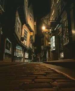 Empty road along buildings at night
