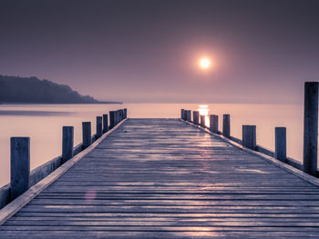 Pier over sea against sky during sunset