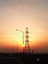 Silhouette electricity pylon against sky during sunset