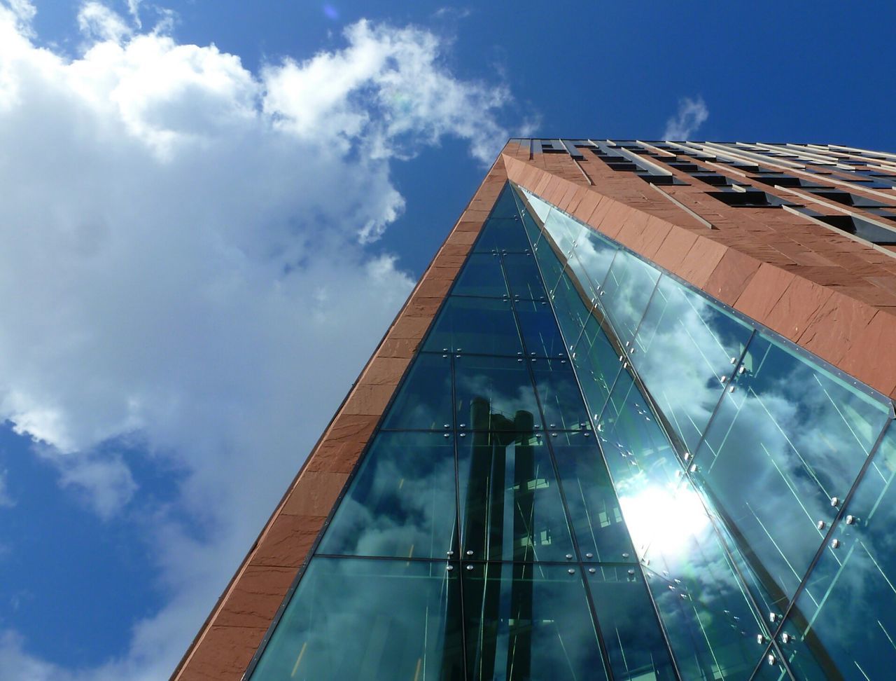 architecture, built structure, low angle view, building exterior, sky, cloud - sky, glass - material, modern, cloud, sunlight, building, reflection, office building, day, city, tall - high, outdoors, no people, blue, directly below