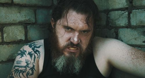 Portrait of angry bearded man against brick wall