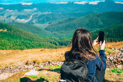 Faceless girl taking photos in mountains. back view of woman blogger in mountain hiking. tourist 