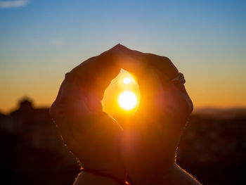 Midsection of woman against sun during sunset