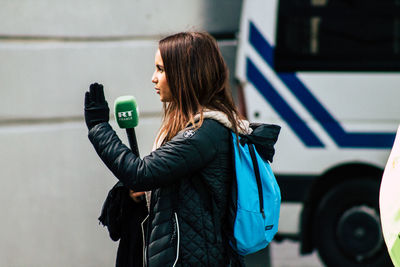 Side view of woman with umbrella standing outdoors