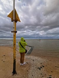 Rear view of woman on beach against sky