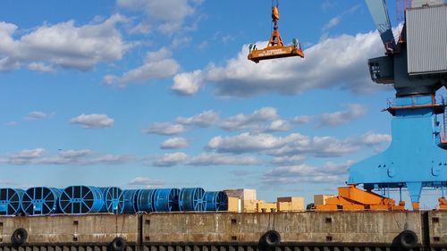 Low angle view of crane against cloudy sky