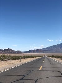 Empty road against clear blue sky