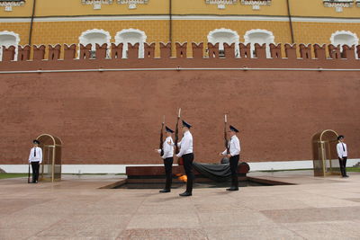 Rear view of people walking outside temple against building