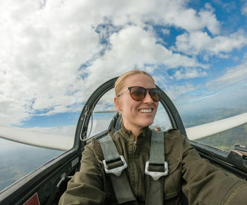 Woman flying airplane against cloudy sky