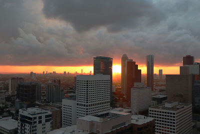 Modern buildings in city against sky during sunset