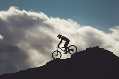 Side view of young male on mountain bike riding over rocks in utah