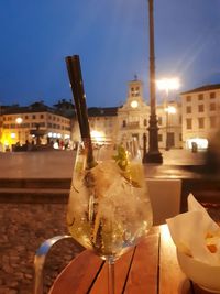 Close-up of drink on table against illuminated city at night