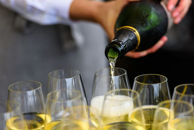 Closeup of a champagne bottle pooring champagne into a champagne flute against a blurred person 