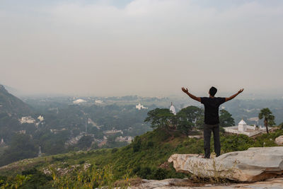 Rear view of man looking at mountain against sky