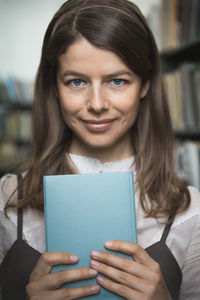 Portrait of young woman holding book