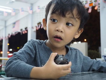 Close-up of boy holding toy while looking away