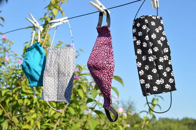 A lot of different colorful self made corona face masks of fabric hanging on clothesline for drying