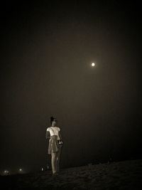 Full length of woman standing at beach against sky during night