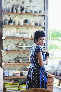 Portrait of young woman wearing polka dot dress while standing in ceramics market