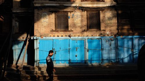 Side view of man standing against building