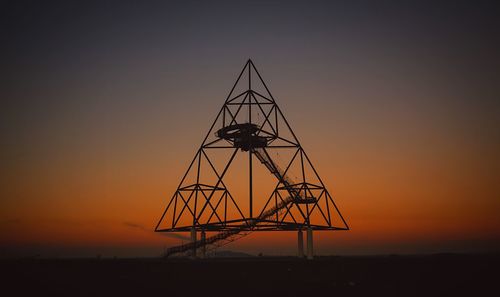 Silhouette cranes against sky during sunset