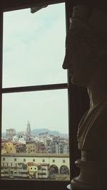 Buildings against sky seen through window