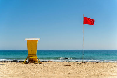 Lifeguard hut on beach against clear blue sky