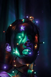 Close-up portrait of young woman in illuminated nightclub