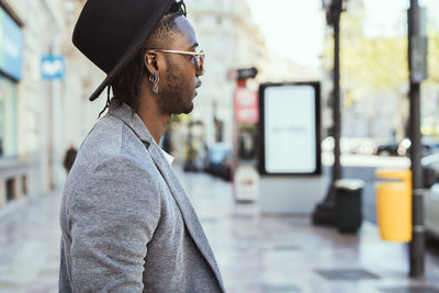 Side view of young man looking away in city