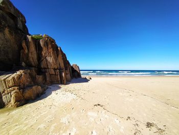 Scenic view of beach against clear blue sky
