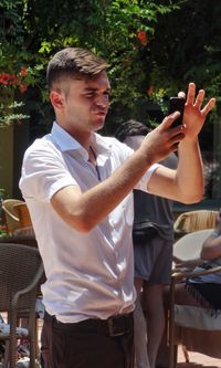 Midsection of man holding mobile phone while standing on table