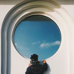 Rear view of boy looking through window