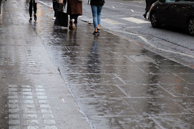 Low section of woman walking on wet road in rainy season