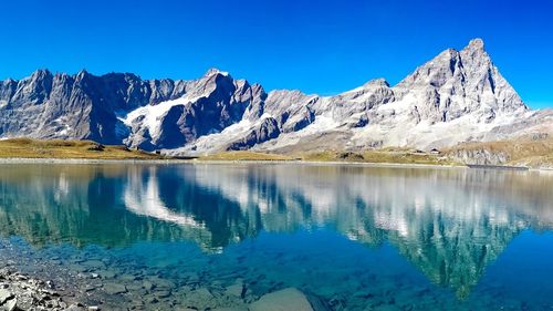 Scenic view of lake and mountains against clear blue sky