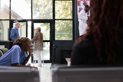 Rear view of woman using mobile phone at table