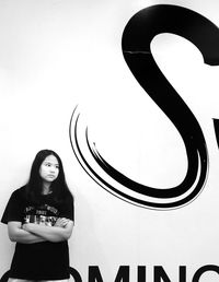 Portrait of young woman standing against wall