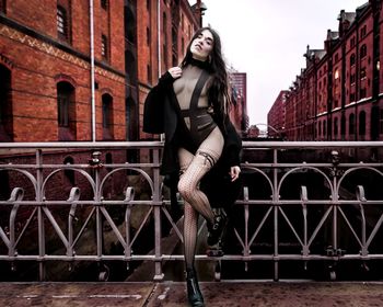 Portrait of woman standing against railing