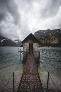 Pier on lake against cloudy sky