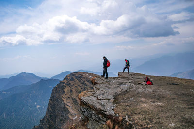 People standing on rock against sky