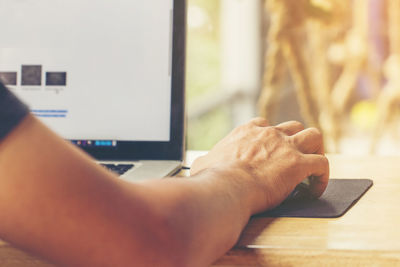 Close-up cropped image of person using computer in office