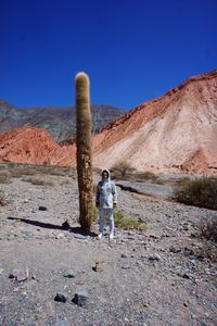 Man standing on dirt road along rocky mountains