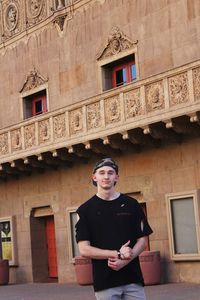 Portrait of young man standing against historic building