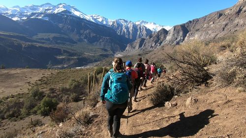 Rear view of people walking on mountain against sky