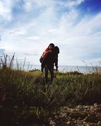 Rear view of couple on field against sky