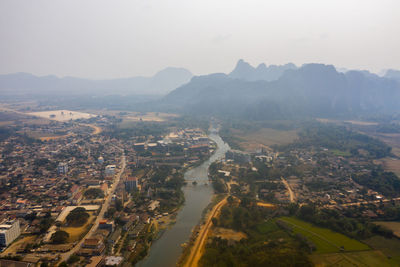 Aerial view of townscape and mountains against sky