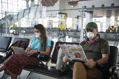 Middle aged man and a young woman wear face masks due to the coronavirus epidemic while waiting at a deserted airport in khajuraho, madhya pradesh, india.