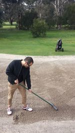 Full length of mid adult man raking sand trap