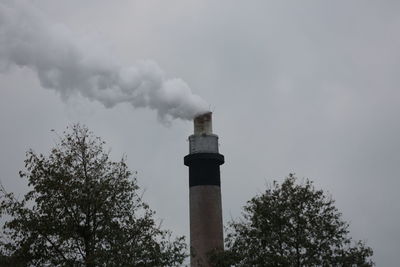 Low angle view of smoke emitting from chimney against sky