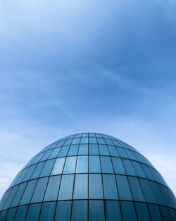 Low angle view of glass building against blue sky
