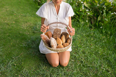 Midsection woman with bread in basket on grass